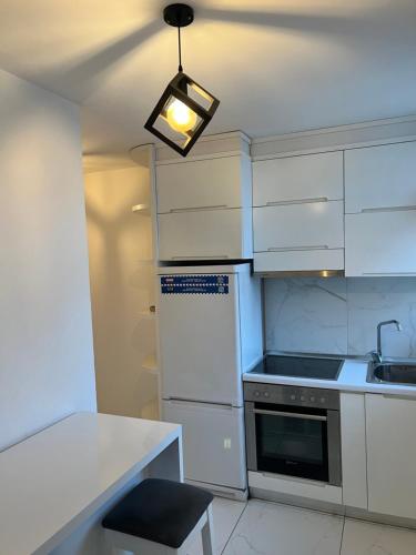 a kitchen with white cabinets and a light fixture at Fila Apartments in Tirana