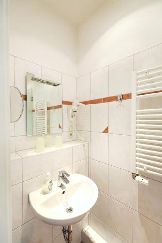 a white bathroom with a sink and a mirror at Appartementhaus Strandnähe in Warnemünde