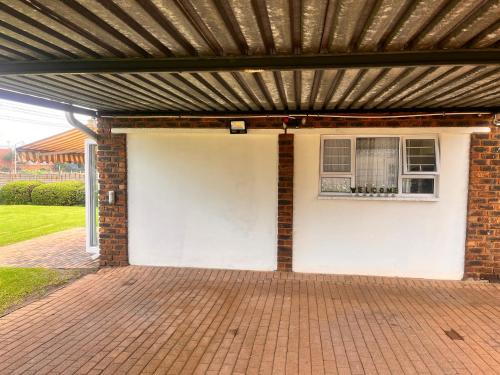 a white garage with awning and a brick building at Aviator's Nest in Kempton Park