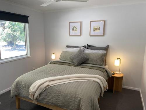 a bedroom with a bed with two lamps and a window at Cycle on Star Lane in Wooragee