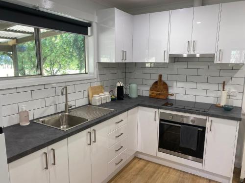 a kitchen with white cabinets and a sink and a window at Cycle on Star Lane in Wooragee