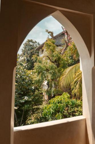 an arched window looking out at a garden at Banana House and Wellness Centre in Lamu