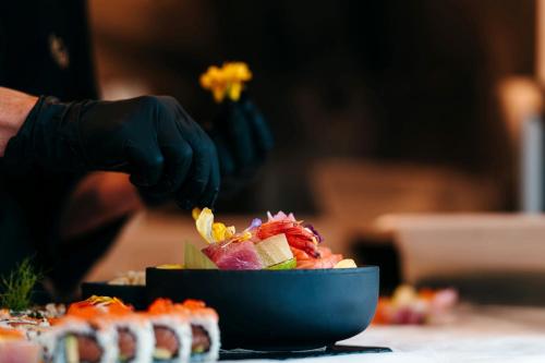 a person wearing gloves preparing a bowl of food at Mangia's Brucoli, Sicily, Autograph Collection in Brucoli