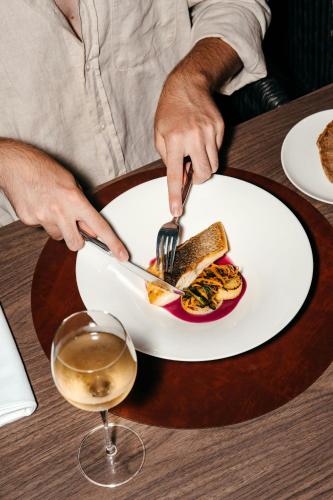 a man eating a plate of food with a fork and knife at Mangia's Brucoli, Sicily, Autograph Collection in Brucoli