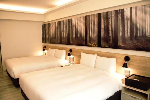 two beds in a hotel room with a painting on the wall at Yoyo Hotel in Chiayi City