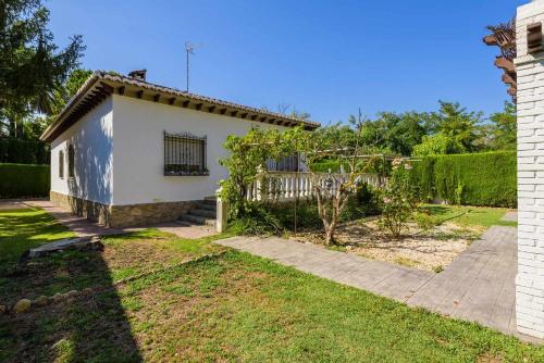 a small white house with a fence and a yard at Casa San Rafael, magnífico chalet con gran jardín in Navajas