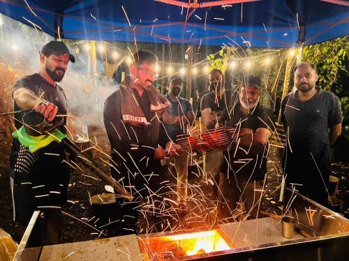 a group of men standing around a barbecue grill at Bambus Alley in Wayanad