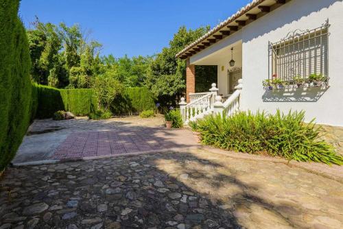a driveway leading to a white house with a fence at Casa San Rafael, magnífico chalet con gran jardín in Navajas