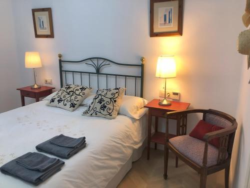 a bedroom with a bed with two lamps and a chair at Casa San Rafael, magnífico chalet con gran jardín in Navajas