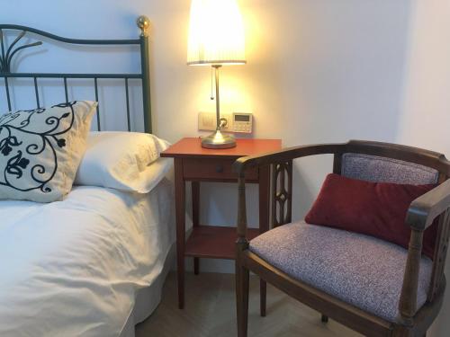 a bedroom with a bed and a table with a lamp and a chair at Casa San Rafael, magnífico chalet con gran jardín in Navajas