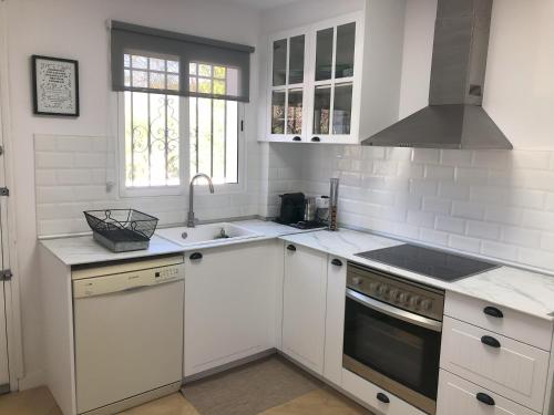 a white kitchen with a sink and a stove at Casa San Rafael, magnífico chalet con gran jardín in Navajas