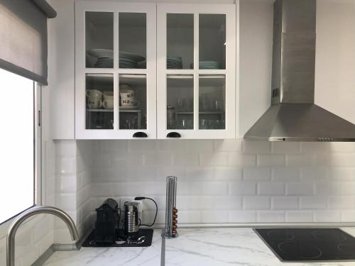 a kitchen with white cabinets with dishes in it at Casa San Rafael, magnífico chalet con gran jardín in Navajas