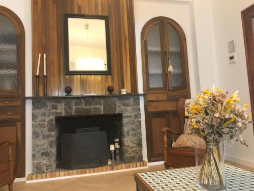 a living room with a fireplace and a vase of flowers on a table at Casa San Rafael, magnífico chalet con gran jardín in Navajas