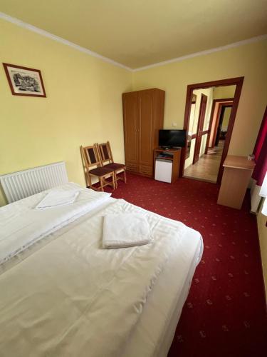 a hotel room with a white bed and a television at Rábensteiner Panzió in Fertőd