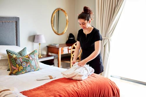 a woman is putting towels on a bed at 9 Hertford Street - 4 Stars VisitEngland in London