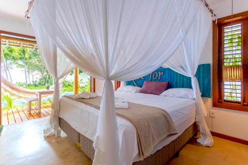 a bedroom with a bed with a canopy at Paraíso Casa Branca in Arraial d'Ajuda