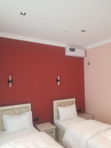 two beds in a room with a red wall at Хотел Пандора in Muruntau