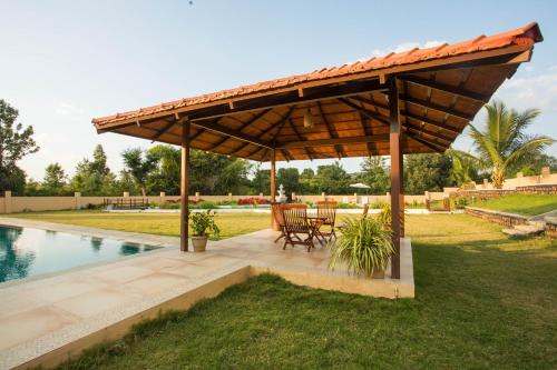 a wooden pavilion with a table and chairs under it at Aeon Root Bridges by Tripture - Villa at Nandi Hills in Nandi