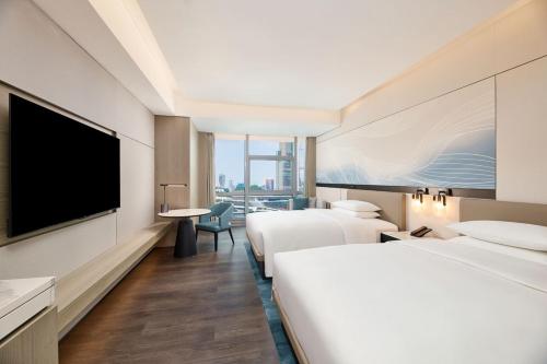 a hotel room with two beds and a flat screen tv at Courtyard by Marriott Zhuhai in Zhuhai