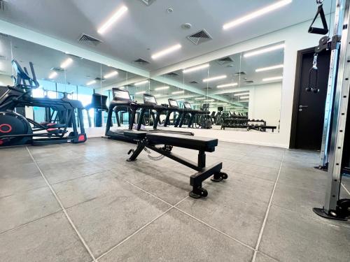 a gym with tread machines and a bench in the middle at Modern 2BR Retreat at The Gate in Masdar City in Abu Dhabi