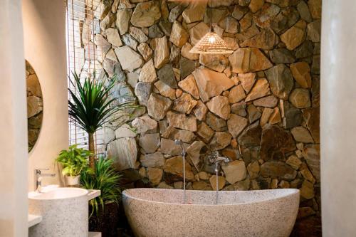 a bathroom with a stone wall and a bath tub at Toàn Cầu Hotel Quảng Bình in Dong Hoi