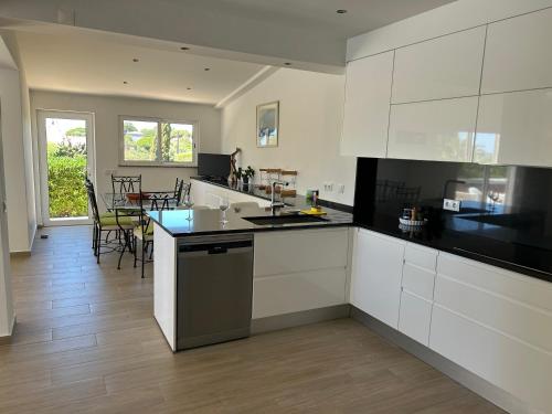 a kitchen with white cabinets and a table with chairs at Peaceful villa with sea view close to Carvoeiro in Carvoeiro