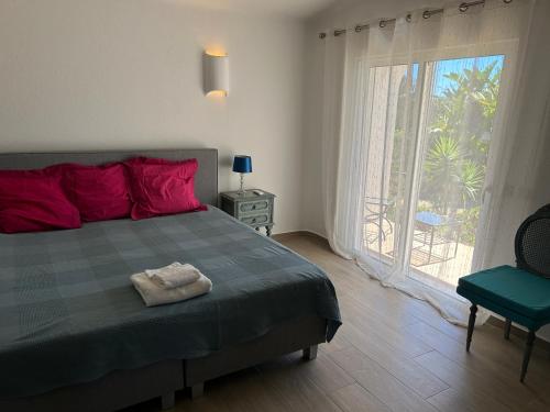a bedroom with a bed with red pillows and a window at Peaceful villa with sea view close to Carvoeiro in Carvoeiro