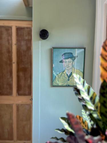 a painting of a man in a hat on a wall at Sfeervolle, historische woonwagen en extra studio in ruime tuin in Rohel