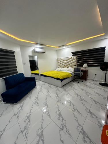 a bedroom with a bed and a blue couch at 2bedroom duplex in OguduGRA by Magnanimous shortlets 15 mins to the airport in Lagos