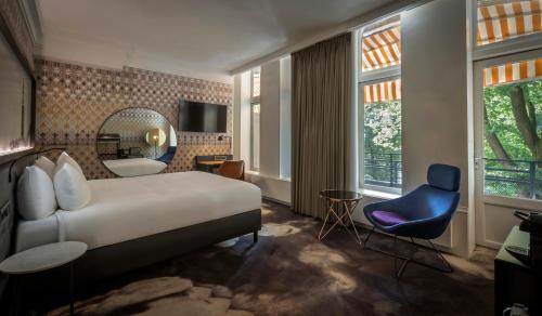 a bedroom with a large bed and a blue chair at Clayton Hotel Amsterdam American in Amsterdam