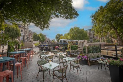a patio with tables and chairs in a city at Clayton Hotel Amsterdam American in Amsterdam