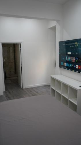 Habitación blanca con TV de pantalla plana en la pared en B&B Scalelle, en Éboli