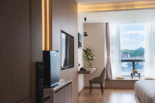 a hotel room with a tv and a bed and a window at Shangge Boya Hotel in Shangri-La