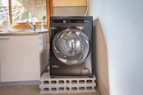 a washing machine in the corner of a kitchen at HANABI棟-BASE棟 サウナ BBQ 農業体験 花火 が楽しめる ペット可 貸し切りで最大12名宿泊可能 Wi-Fi完備 in Katori