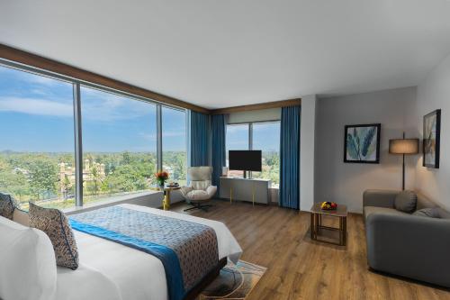 a hotel room with a bed and a couch and windows at Fortune Airport Road Kochi - Member ITC hotels' group in Cochin