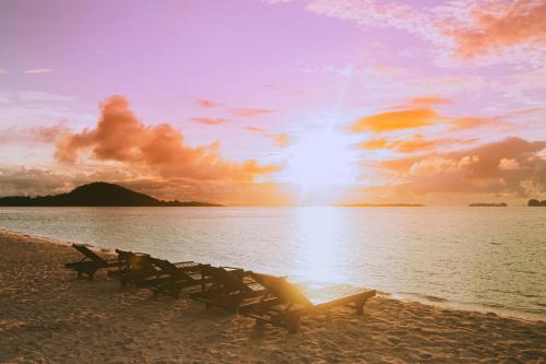 a group of chairs sitting on the beach at sunset at Andau Dive Resort Raja Ampat in Tapokreng
