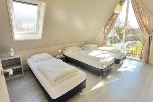 two beds in a room with two windows at Sandy 25 in Callantsoog