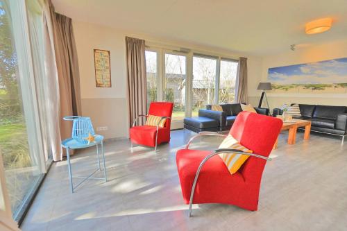 a living room with red chairs and a couch at Sandy 25 in Callantsoog