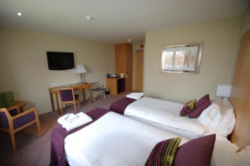 a hotel room with two beds and a television at Kings Court Hotel in Stratford-upon-Avon