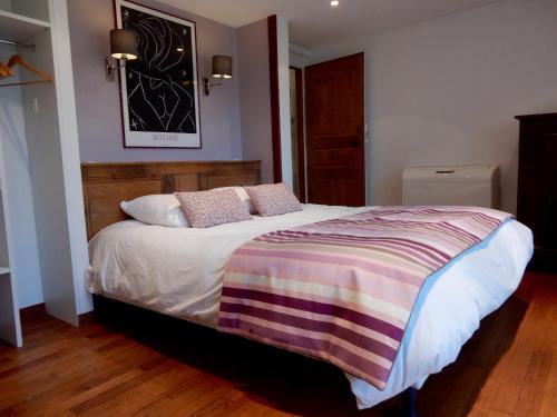 a bedroom with a large bed with a striped blanket at Le Petit Vigneau in Ménil
