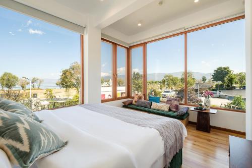 a bedroom with a large bed and large windows at Floral Hotel Dali Ershuang Sea View in Dali
