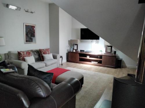 Una sala de estar con un sofá y un televisor. en Apartment 1 - Rivervilla or Apartment 2 - Stone Cottage, en Underberg