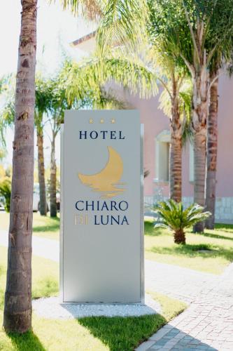 a sign for a hotel with palm trees in the background at Hotel Chiaro di Luna in Marina di Ascea