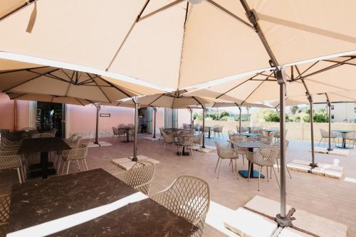 a patio with tables and chairs and umbrellas at Hotel Chiaro di Luna in Marina di Ascea