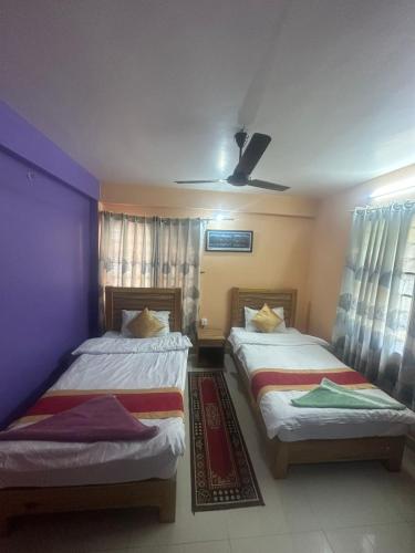two beds in a room with purple walls at Thanapati Guesthouse in Pokhara