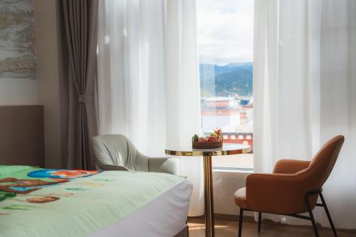 a room with a bed and a table and a window at Shangge Boya Hotel in Shangri-La