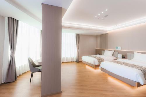 a hotel room with two beds and a chair at Shangge Boya Hotel in Shangri-La