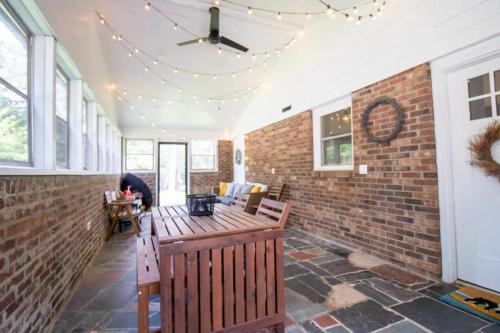 a patio with a wooden table and a brick wall at GVL getaway near Paris Mtn, minutes from downtown in Greenville