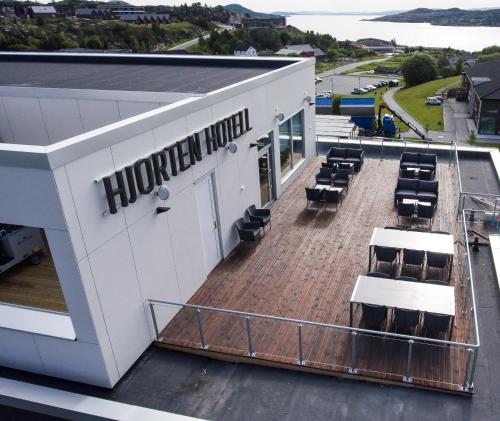 Un edificio con una gran terraza con sillas. en Hjorten Hotell Hitra, en Fillan
