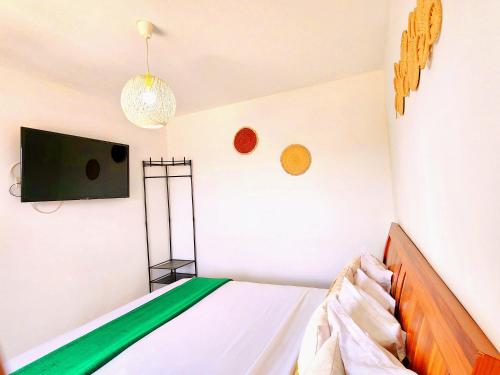 a bedroom with a bed and a tv on the wall at La Casa Di Luna - Hotel with Pool and Restaurant in Antananarivo in Antananarivo